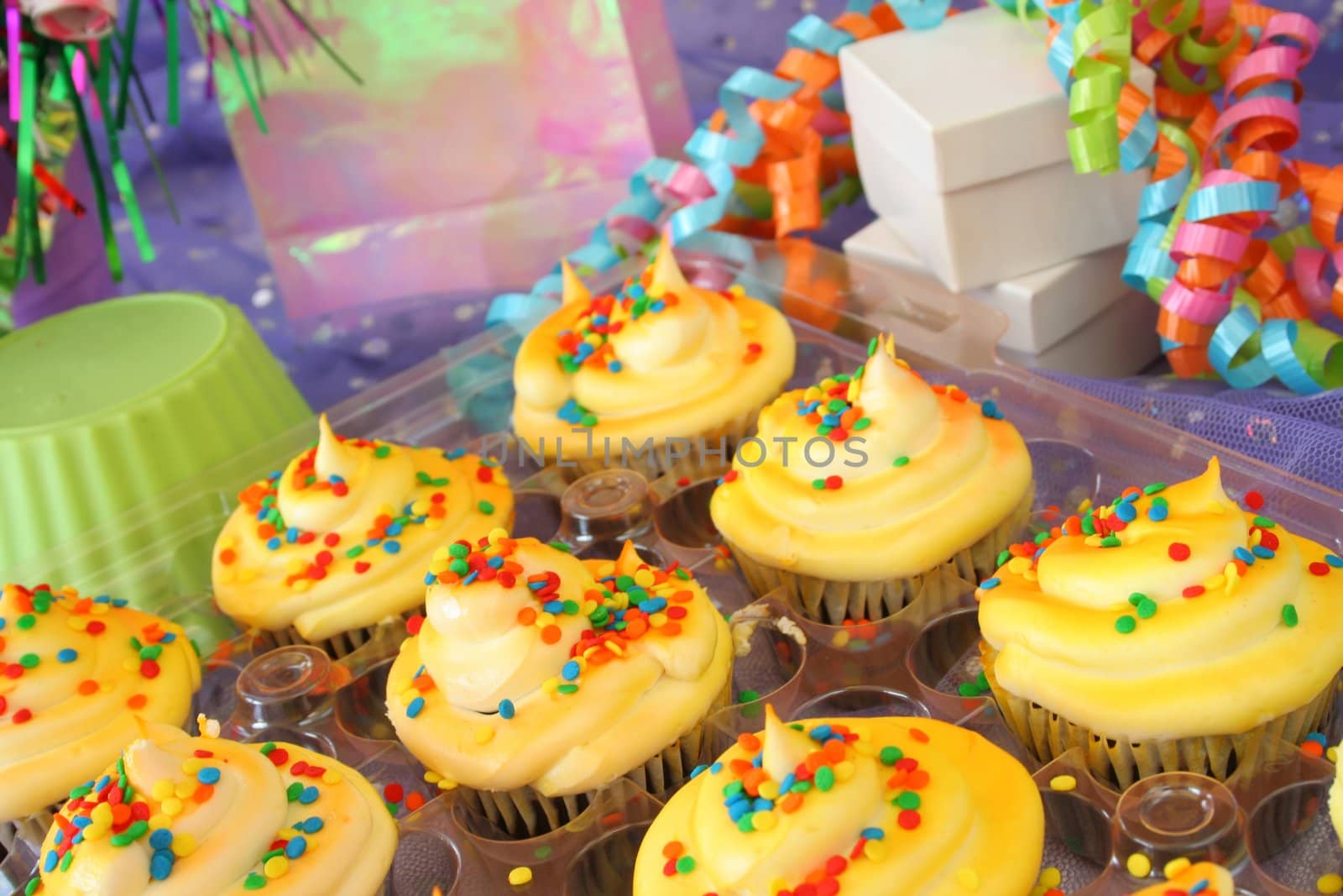 A grouping of beautifully colored cup cakes with sprinkles and party supplies.  Used a shallow DOF and selective focus.