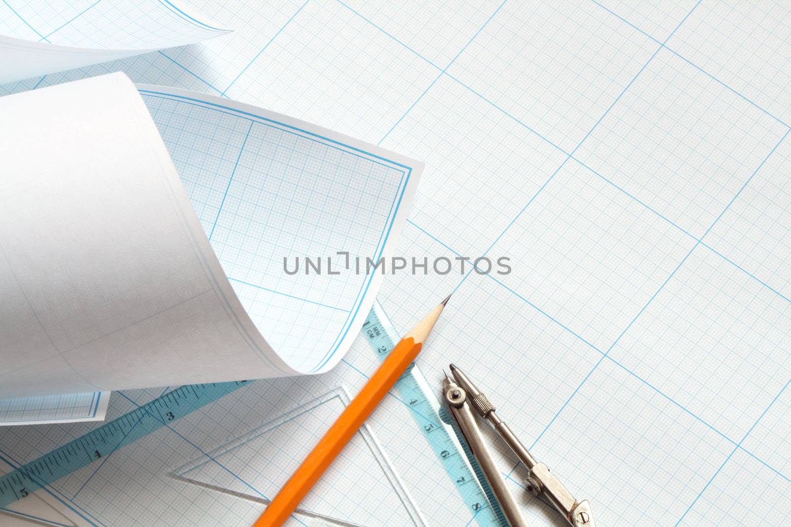 Divider, pencil and ruler on blue graph paper background