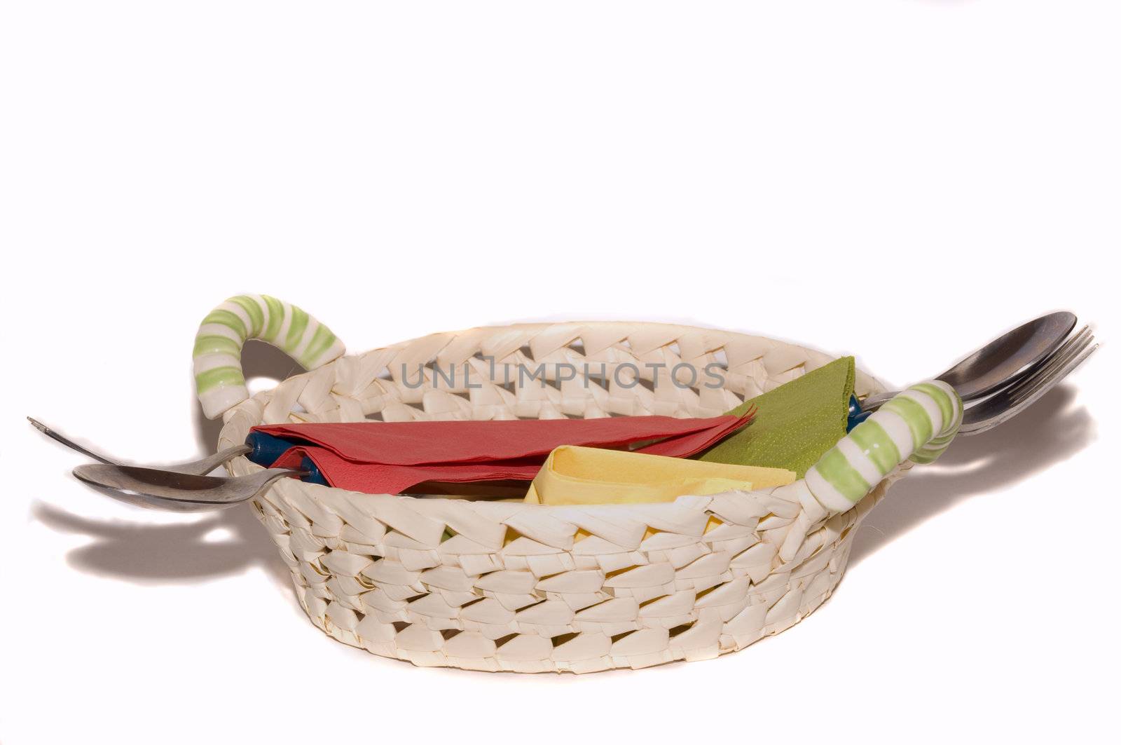 basket with cutlery and colored napkins on white background