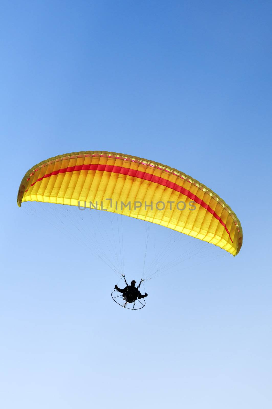 Man with a yellow paraglider flying in the sky