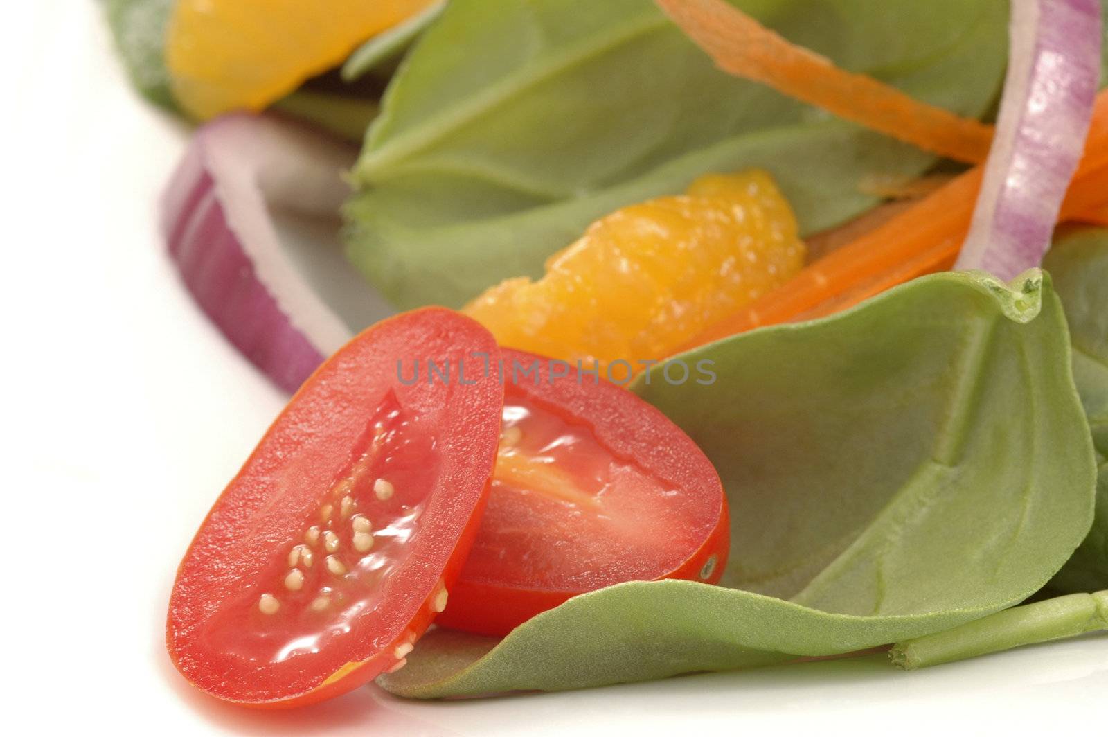 Halved tomato with colorful salad in the background.