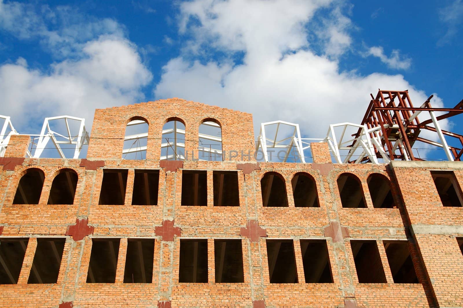 building of red brick under construction and blue sky in window frames