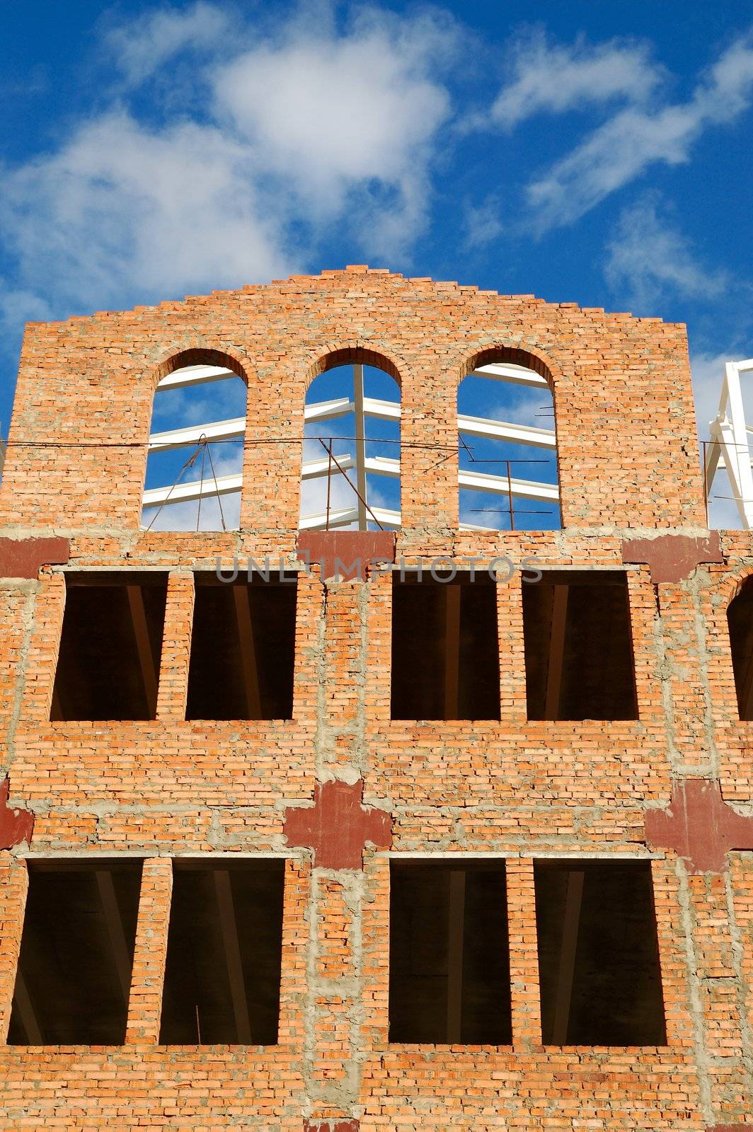 building of red brick under construction and blue sky in window frames
