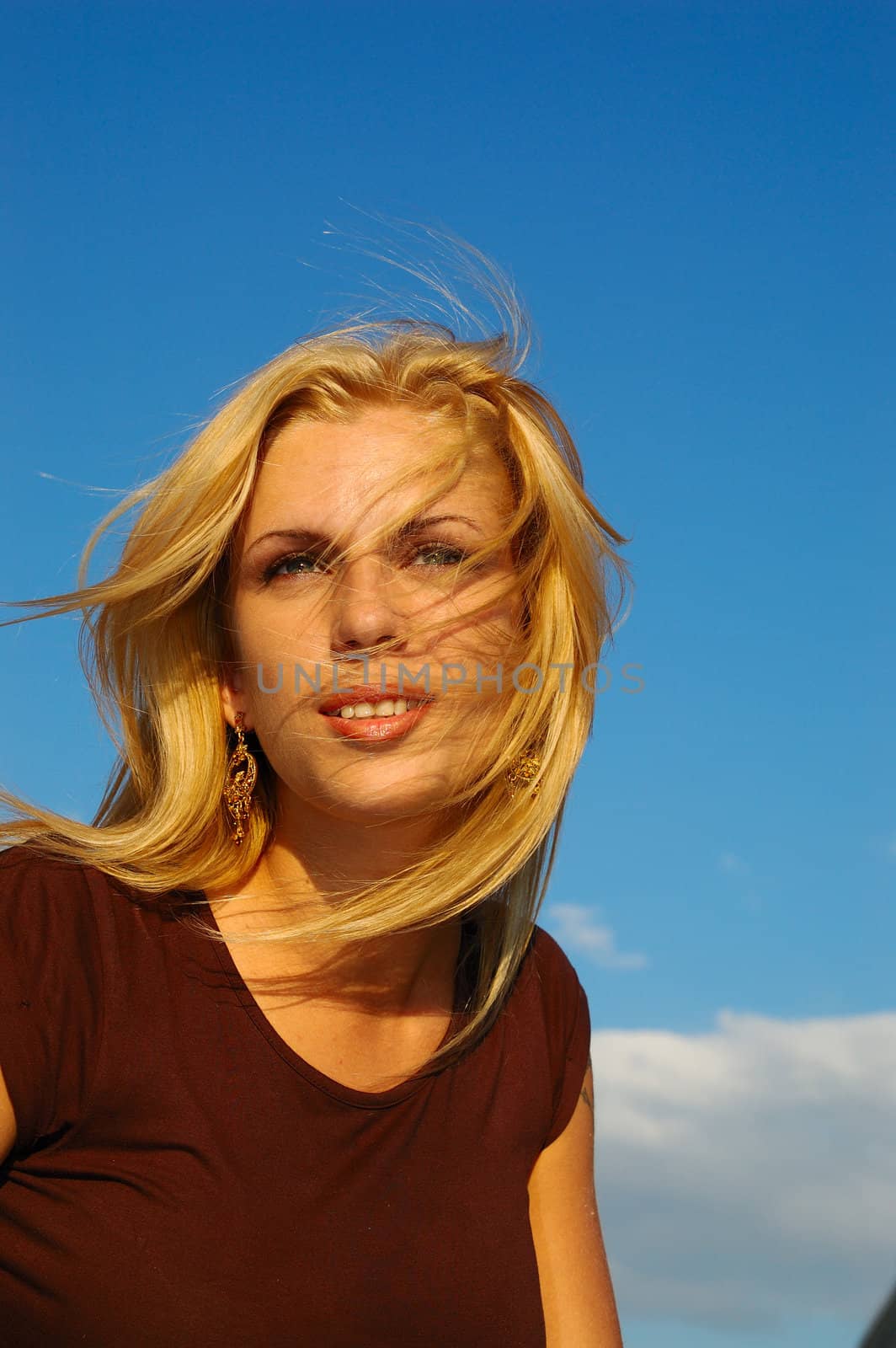 blond woman with fly-away hair against blue sky