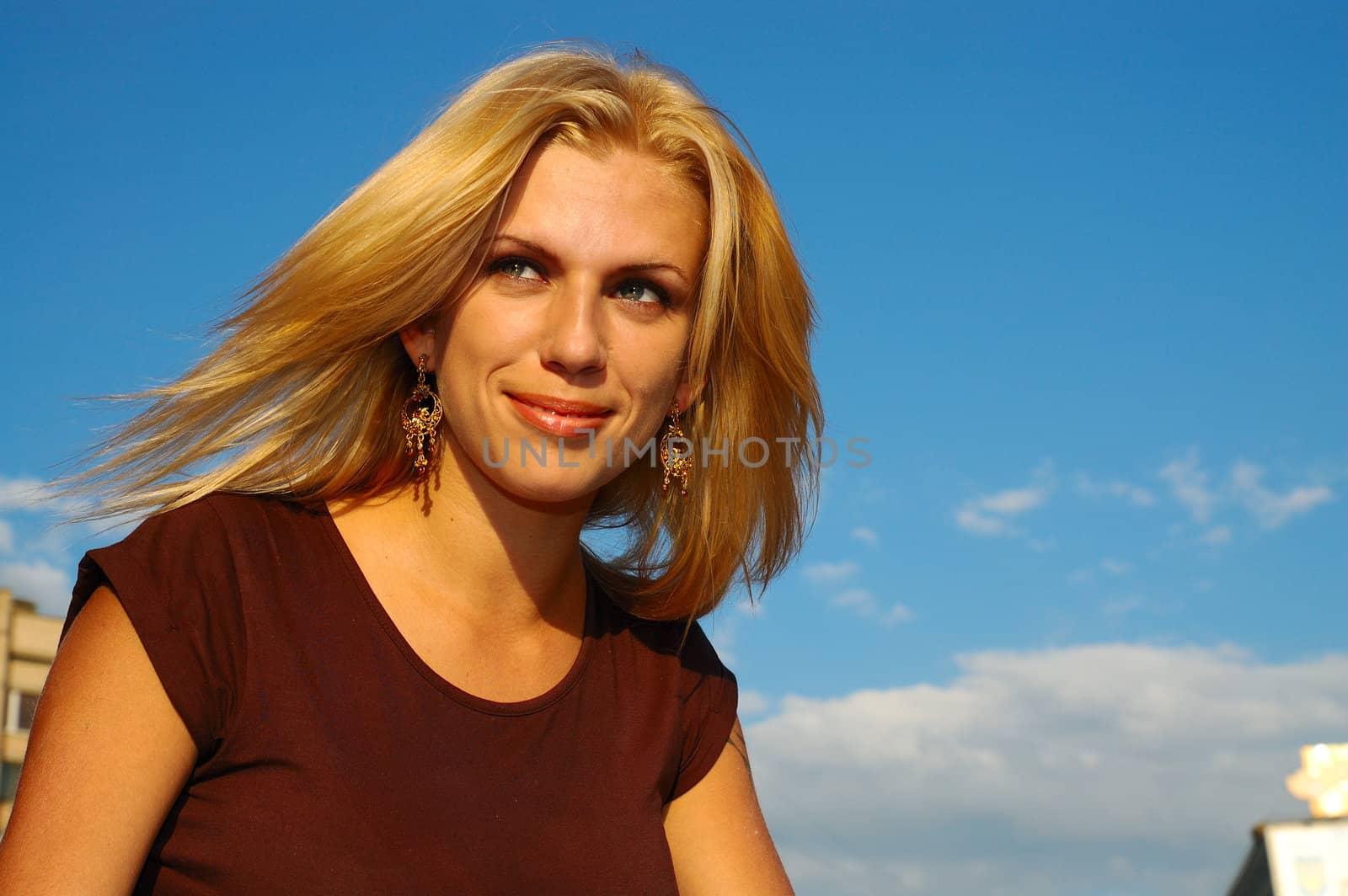 Smiling blond woman with fly-away hair against blue sky