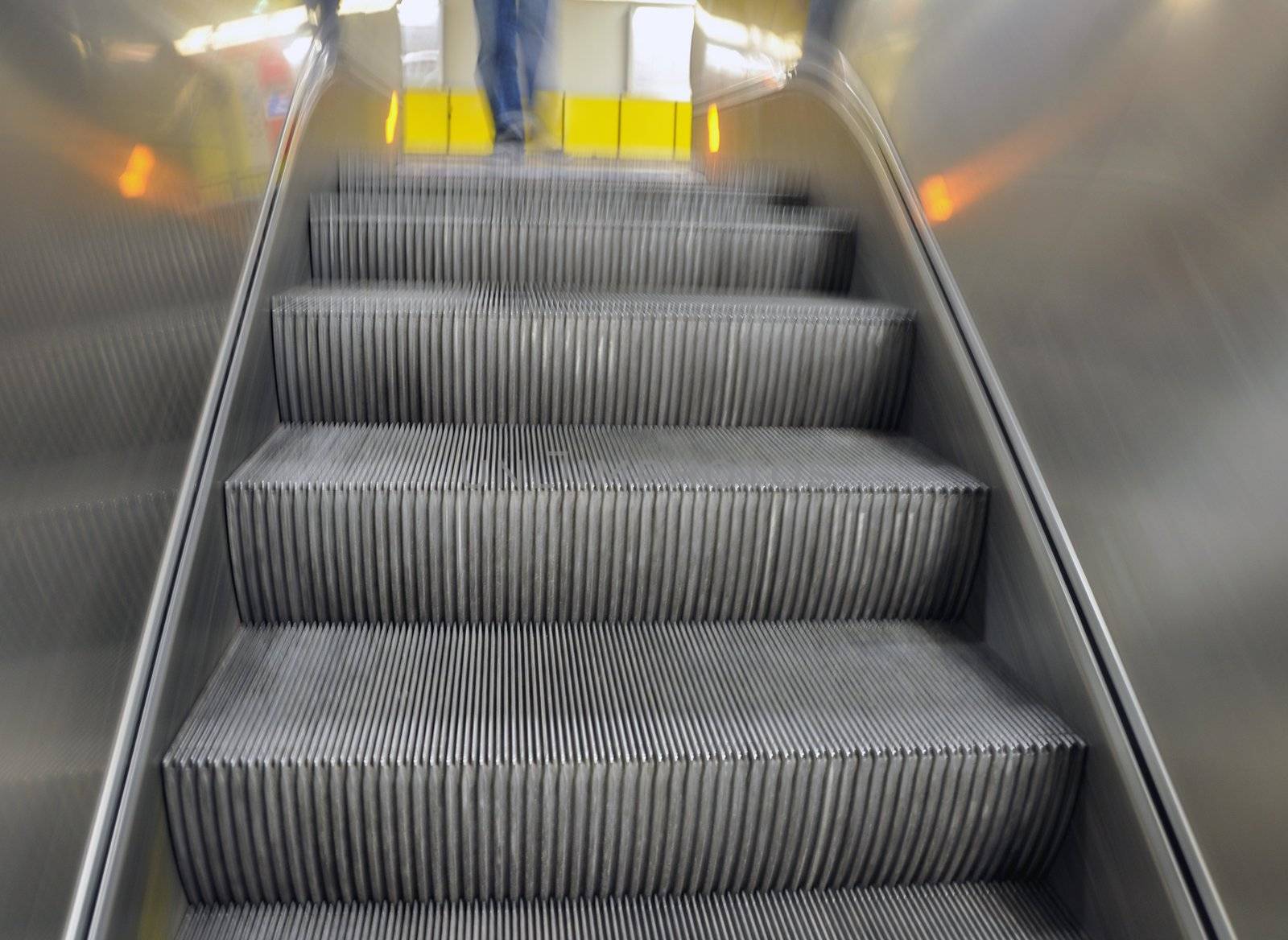 Foto of an escalator moving down from a bright yellow floor