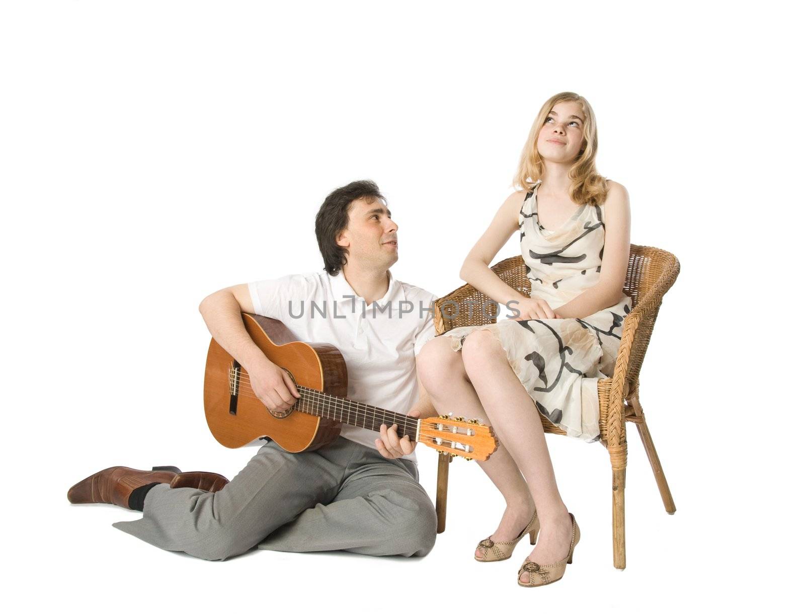 A blond girl and a man playing guitar for her