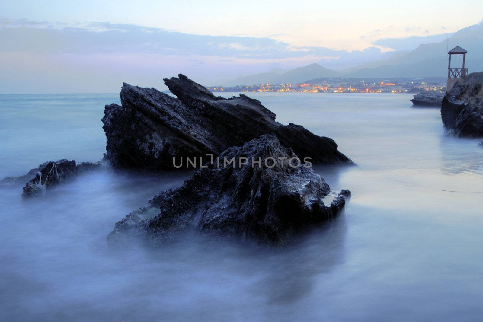 Rocks on at evening shoreline in water and mist at. Crete, Greece. 