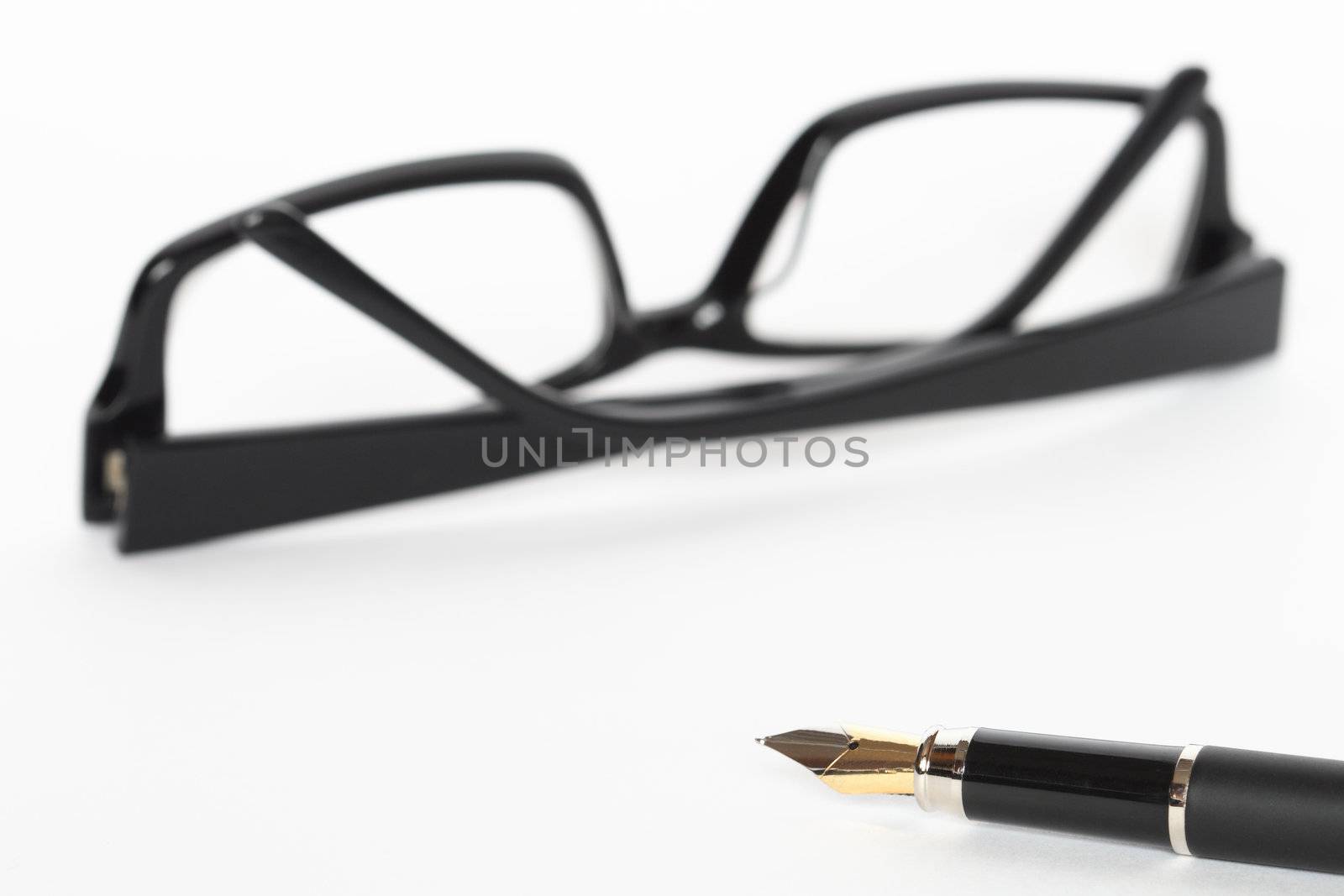 Closeup of fountain pen lying on white background with black spectacles