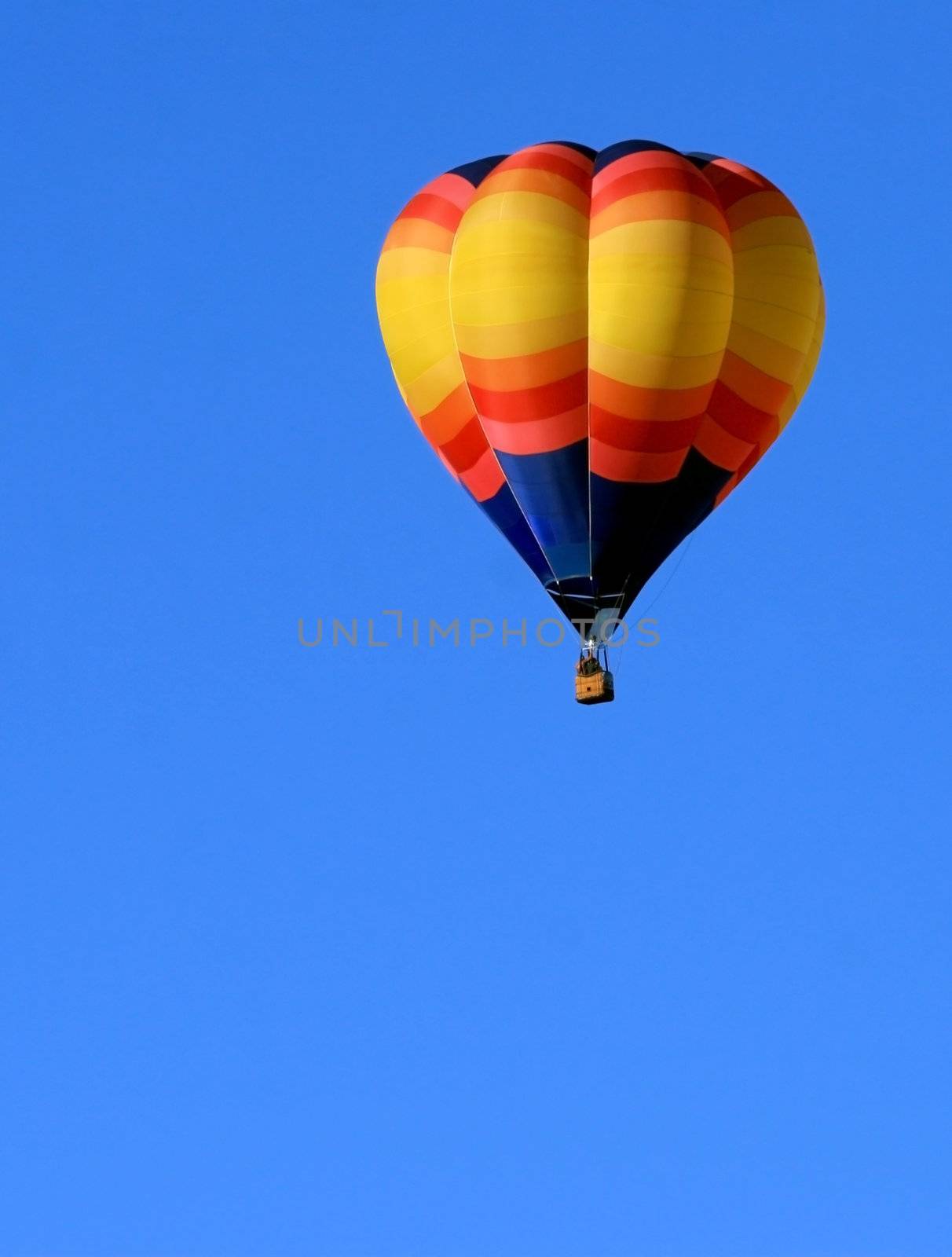 Colorful hot air balloon in brilliant blue sky with plenty of copy space