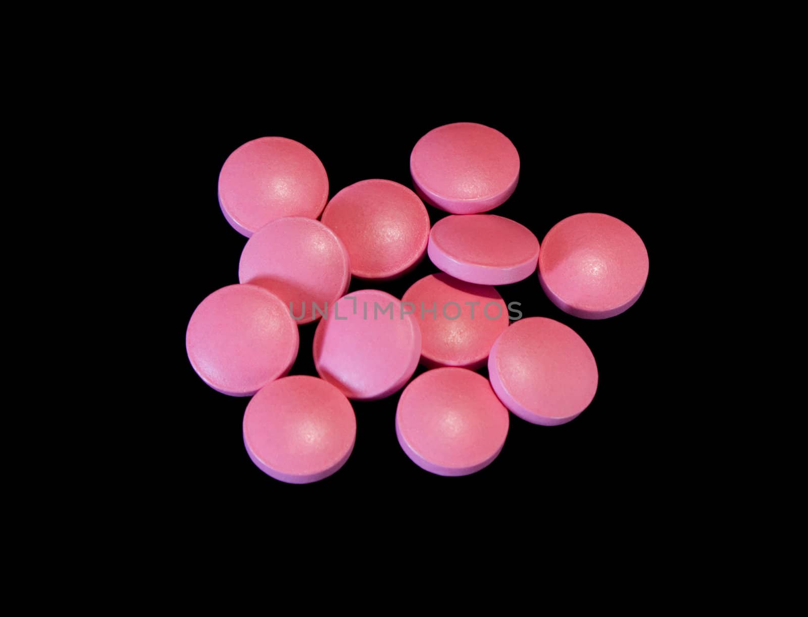 Pile of pink pills isolated on black background