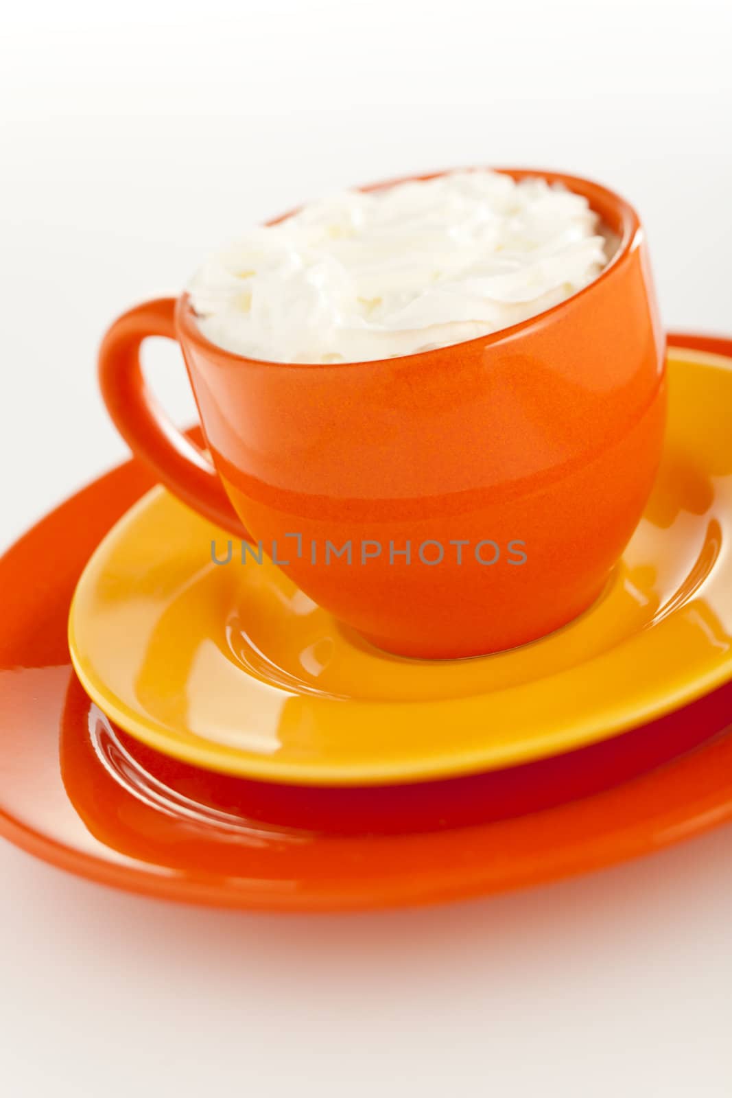 Orange coffee cup with yellow plate over white background