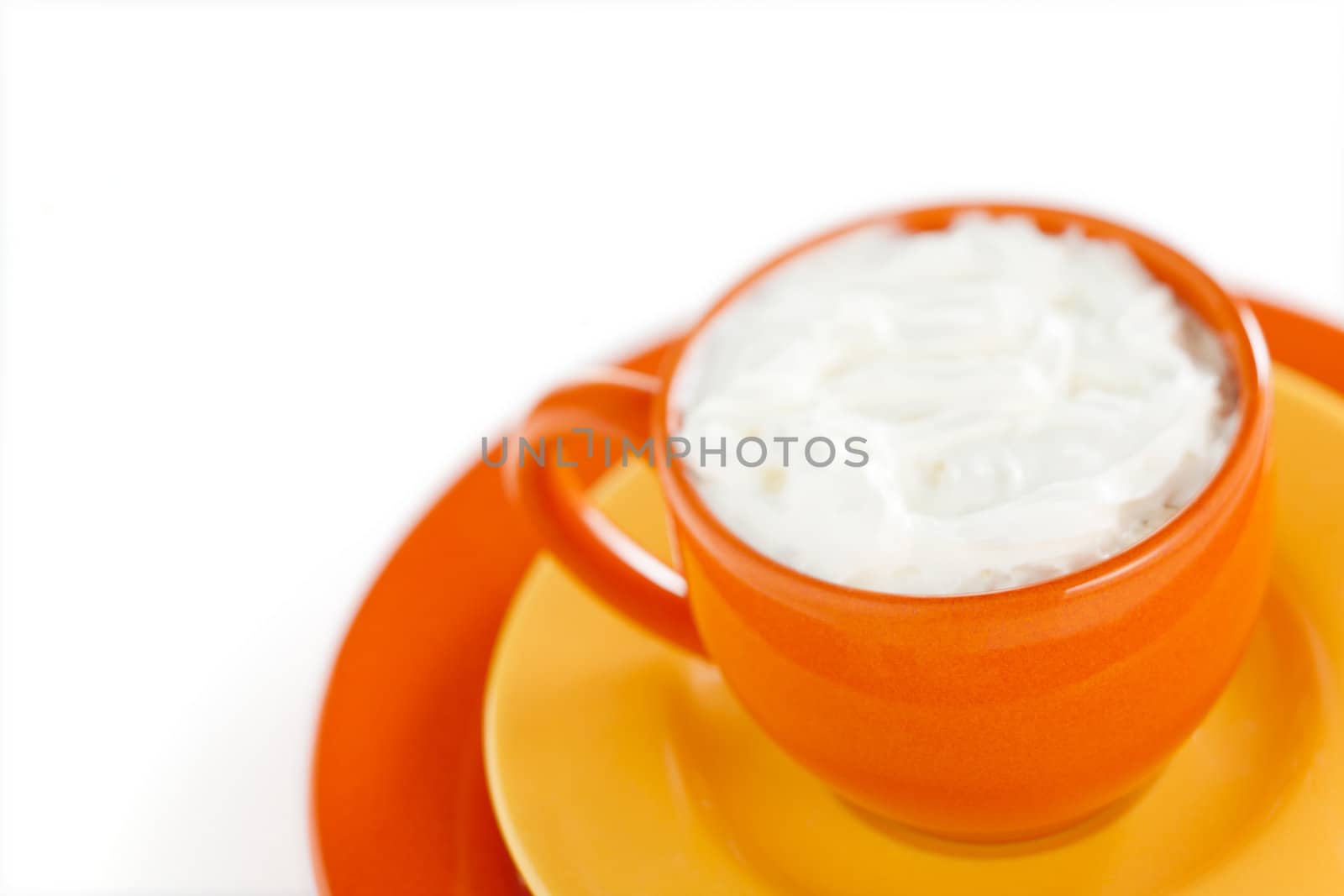 Orange coffee cup with yellow plate over white background