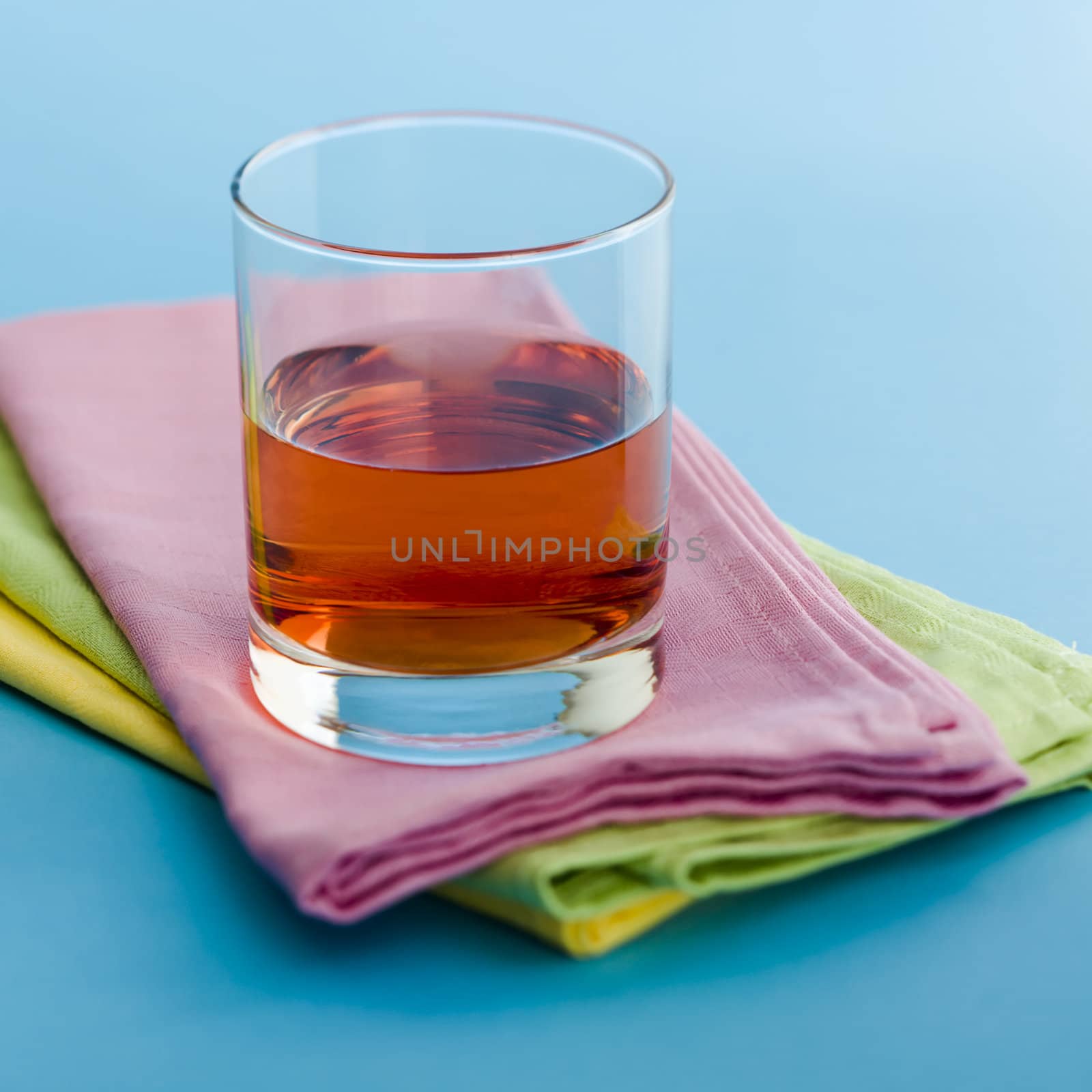 Glass of cranberry juice on pile of napkins