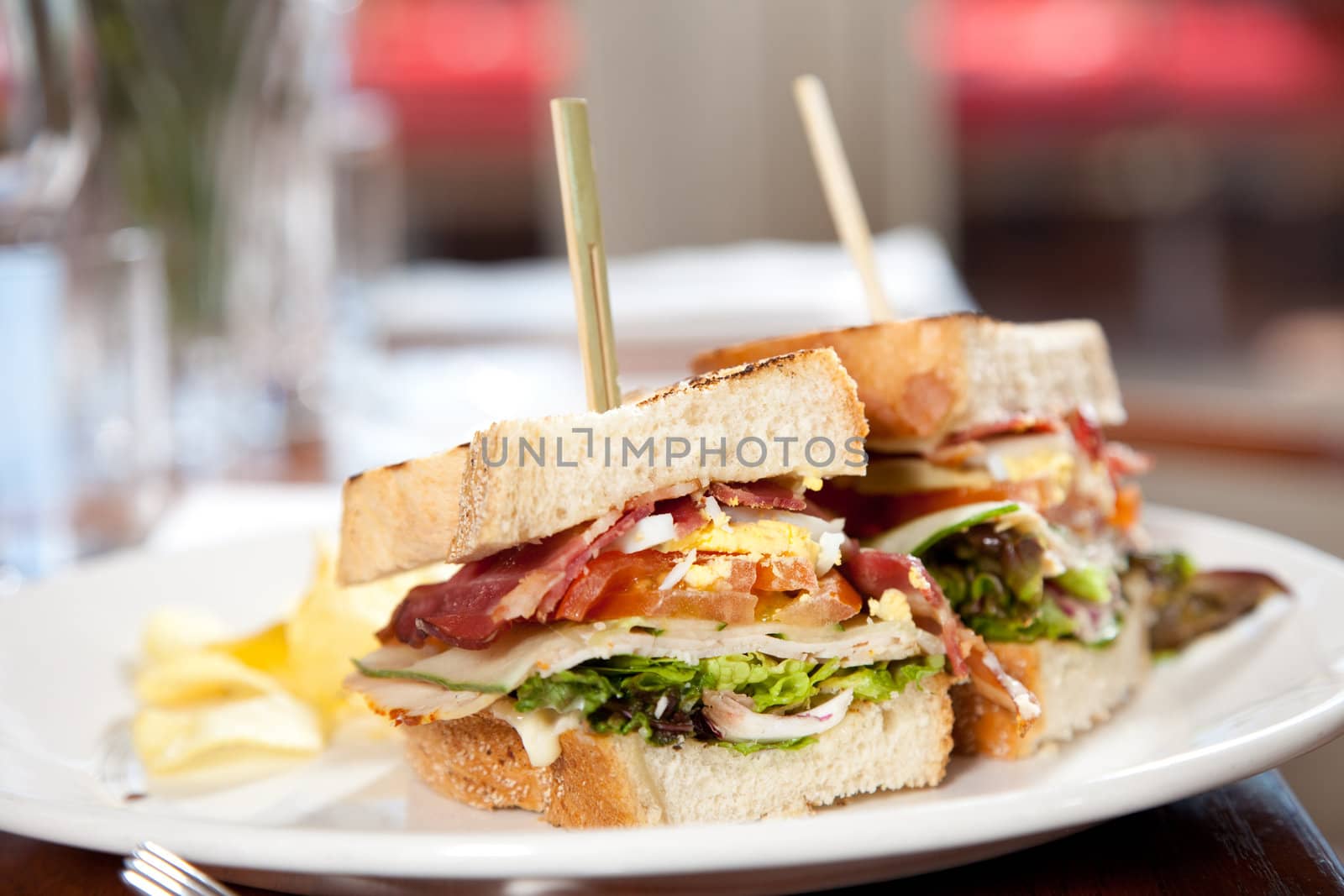 Delicious clubsandwich with toasted bread, bacon, egg, and chips