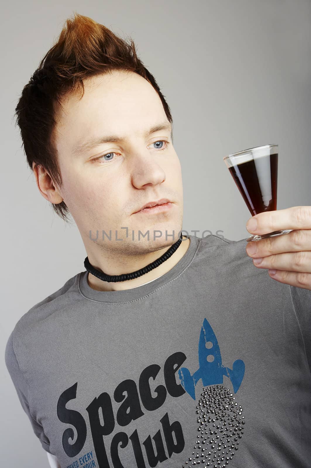 Tired man drinking a small shot of hard liquer