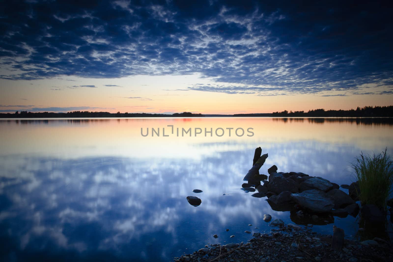 Sunset on rocky beach with cloud reflections