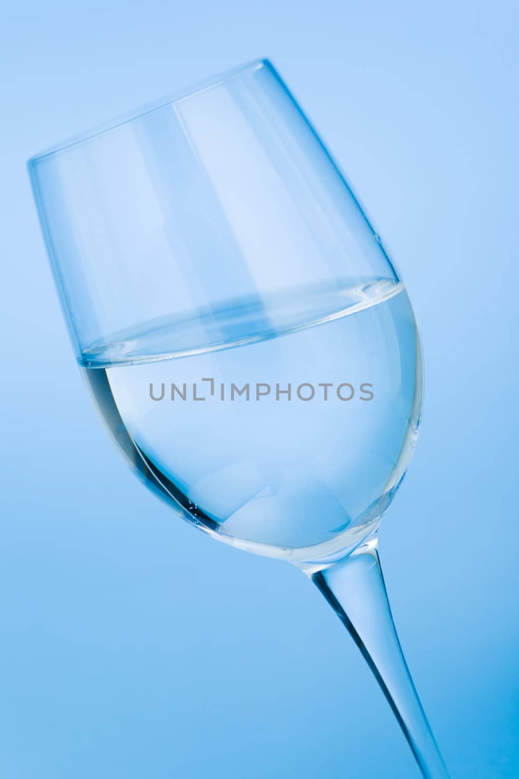 Wine glass filled with water over blue background