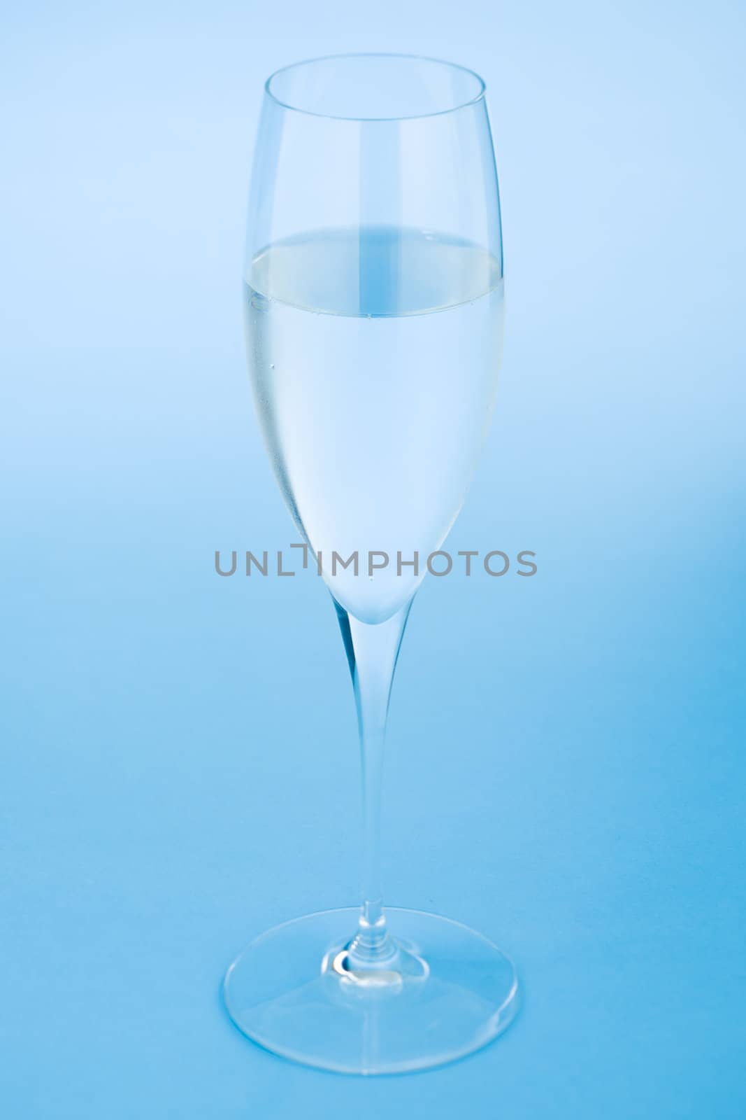 Sparkling wine glass filled with water over a blue background