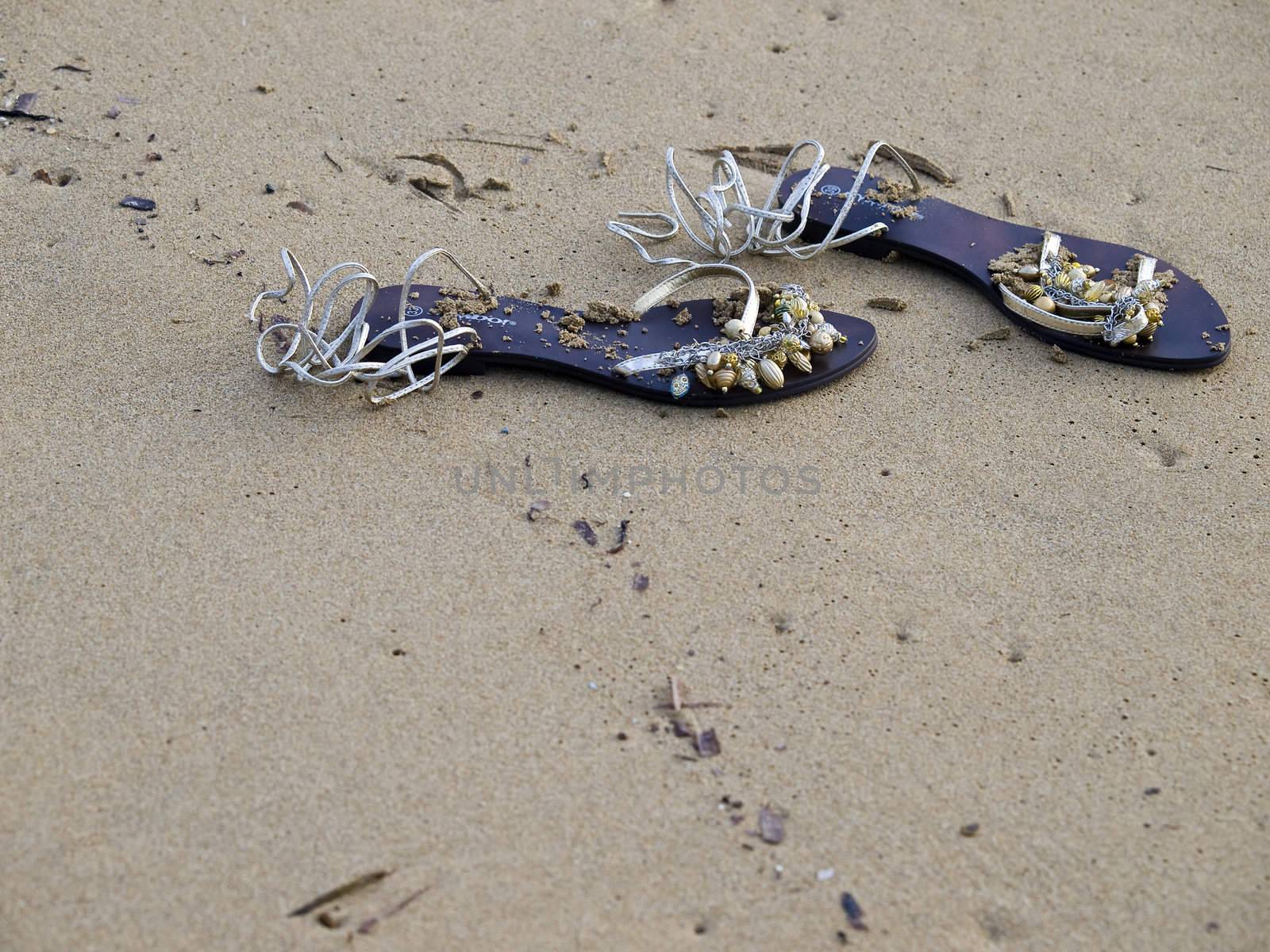 Beautiful beach sandals adorned in shells lying on a beach