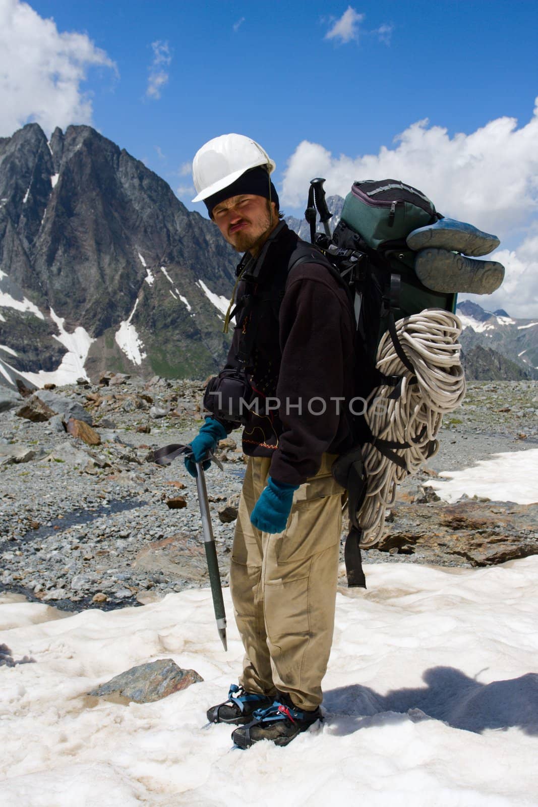 Climber in crampon and helmet standing on snow in mountains