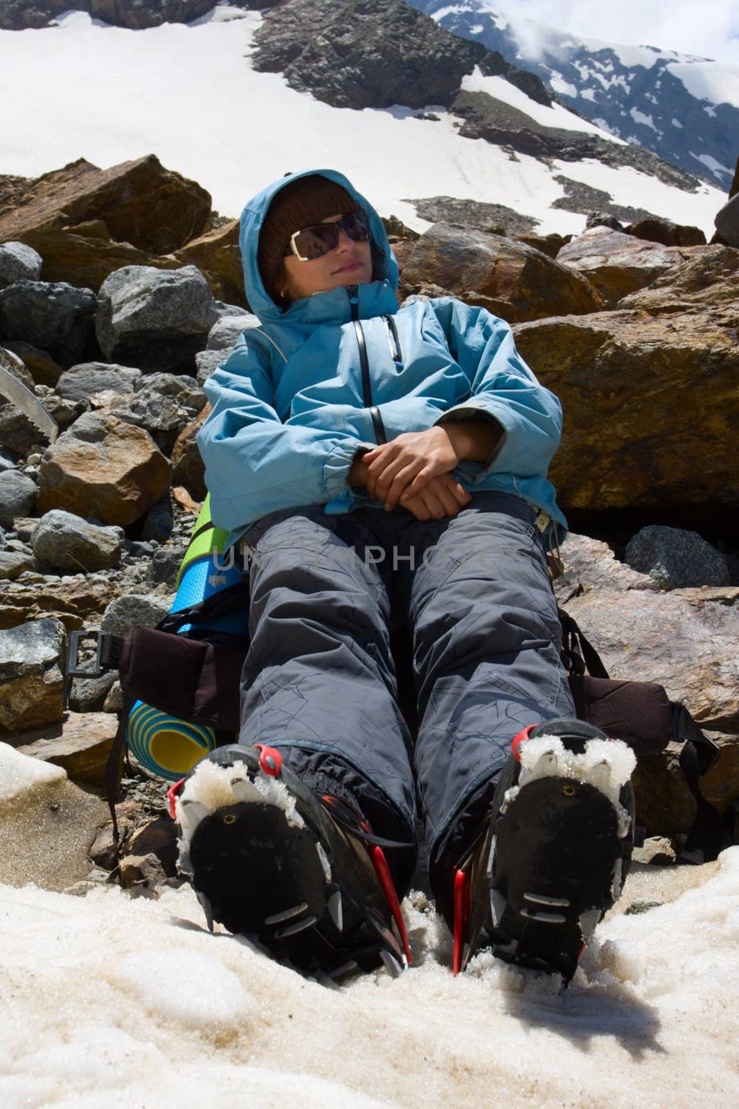 Girl in crampon relaxing on snow in mountains