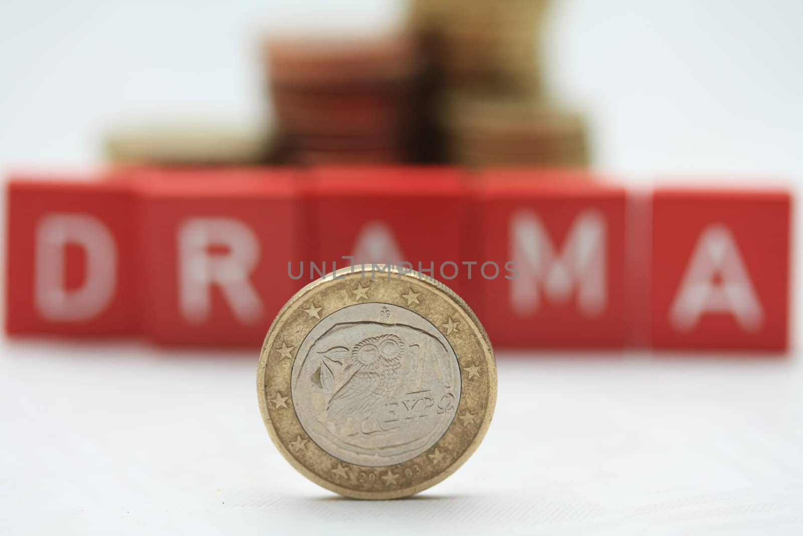 A greek euro coin in front of letters spelling the word "drama", expressing the financial crisis and problems in Greece