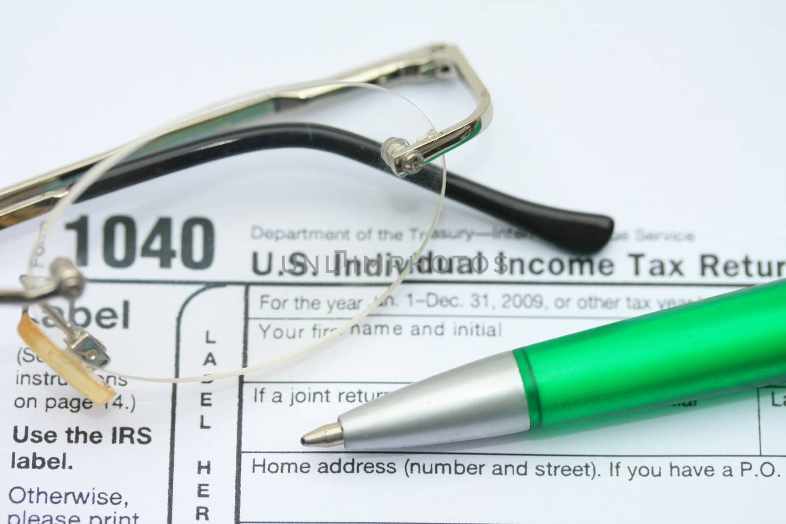 A pair of glasses and a green pen on an income tax return form 