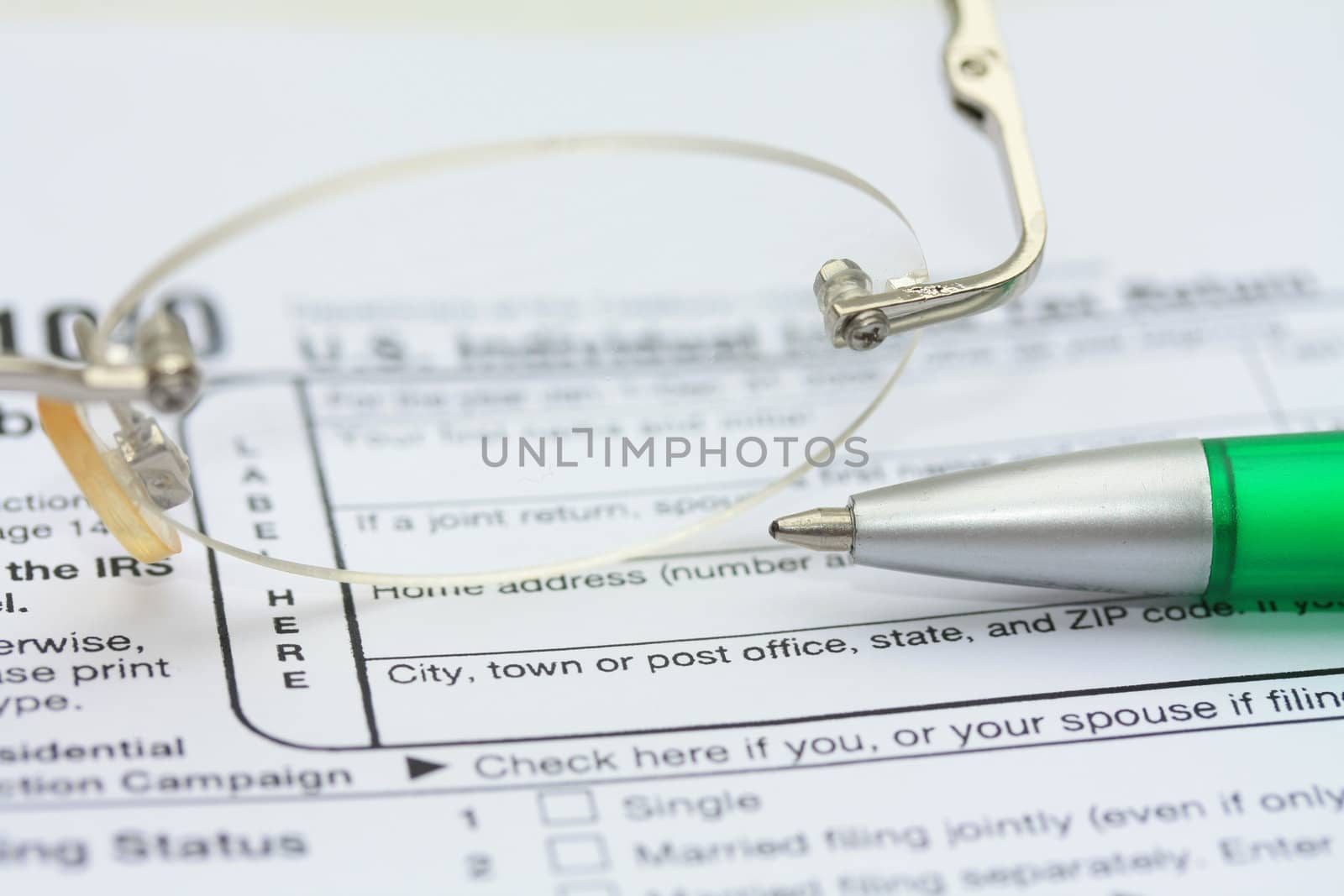 A pair of glasses and a green pen on an income tax return form