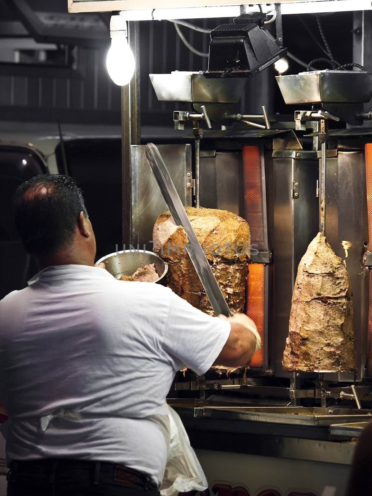 Roadside shish kebab kiosk vendor slicing freshly cooked meat