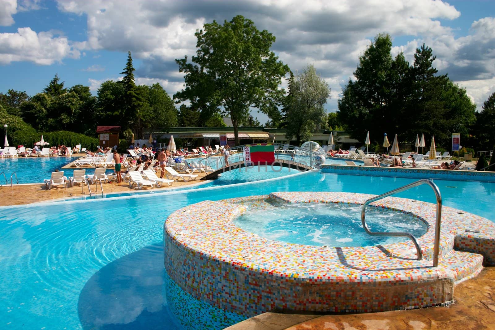 Hotel pool with blue water and sunburning peoples around