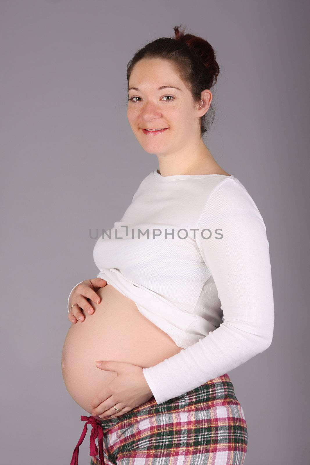 pregnant woman holding belly on grey background