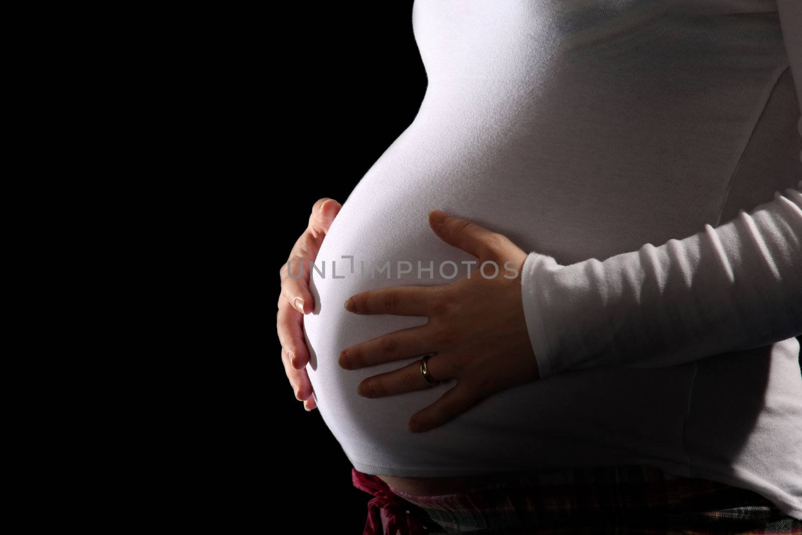 pregnant woman holding belly on black background