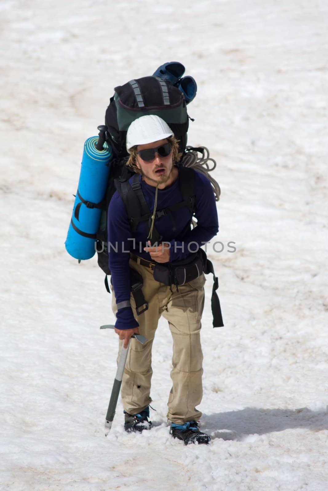 exhausted extreme tourist climbing on snowy mountain
