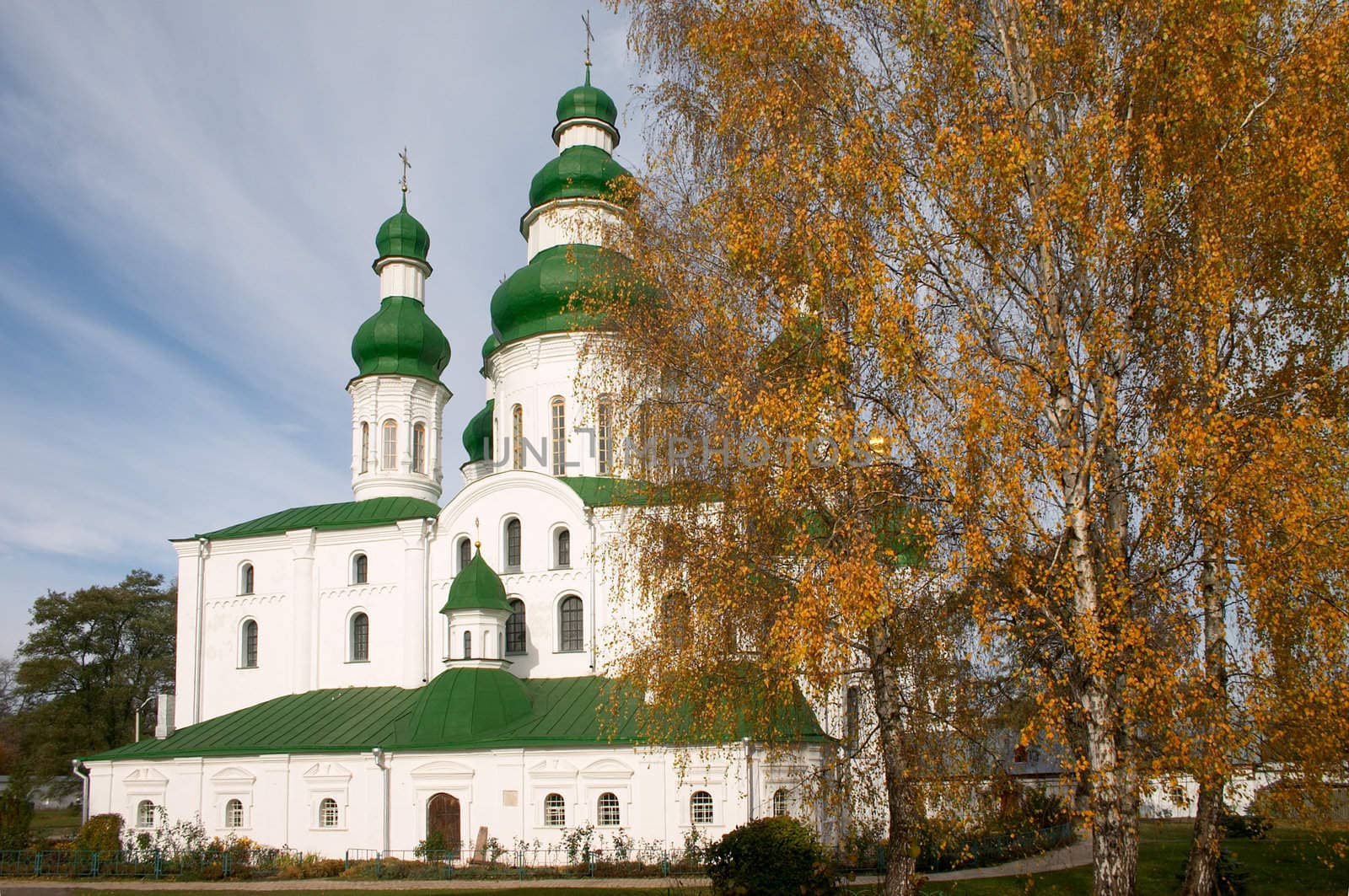 old church and golden fall tree near of it