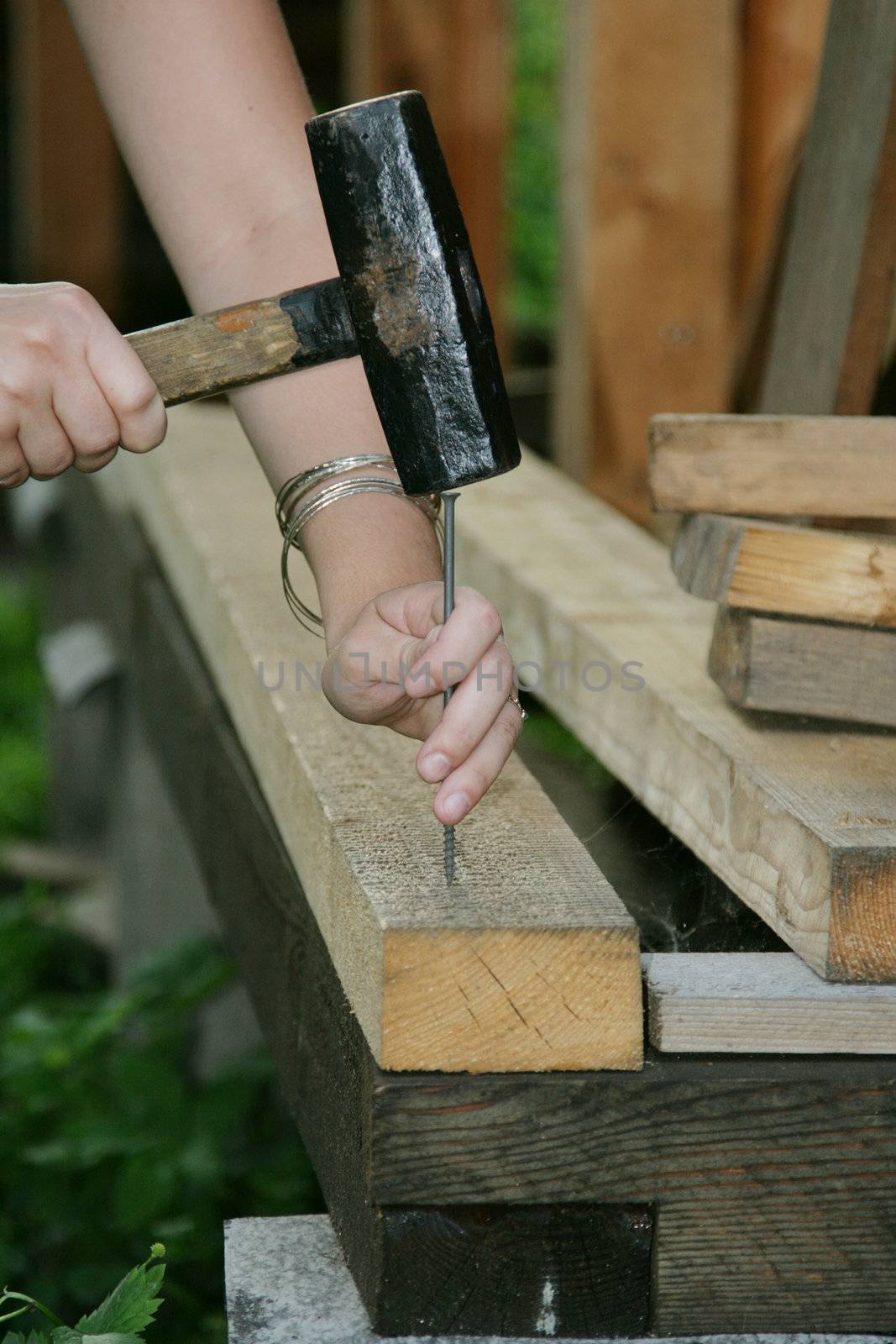 The person hammers in a nail into a wooden floor