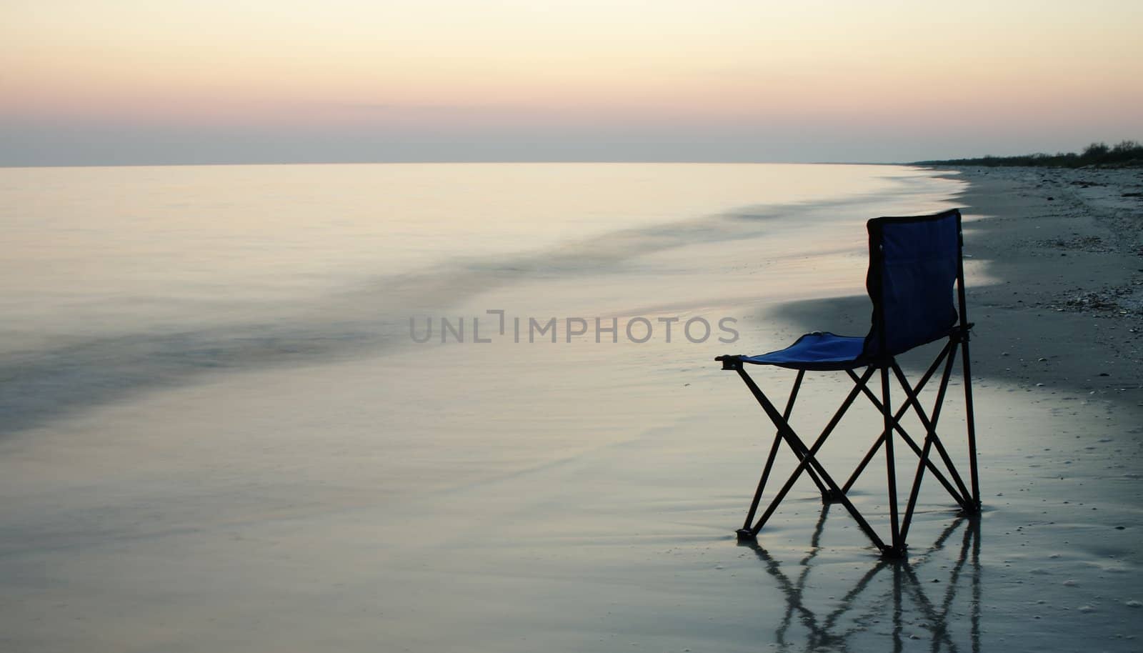 Folding chair standing on a wet sand on a seaside 