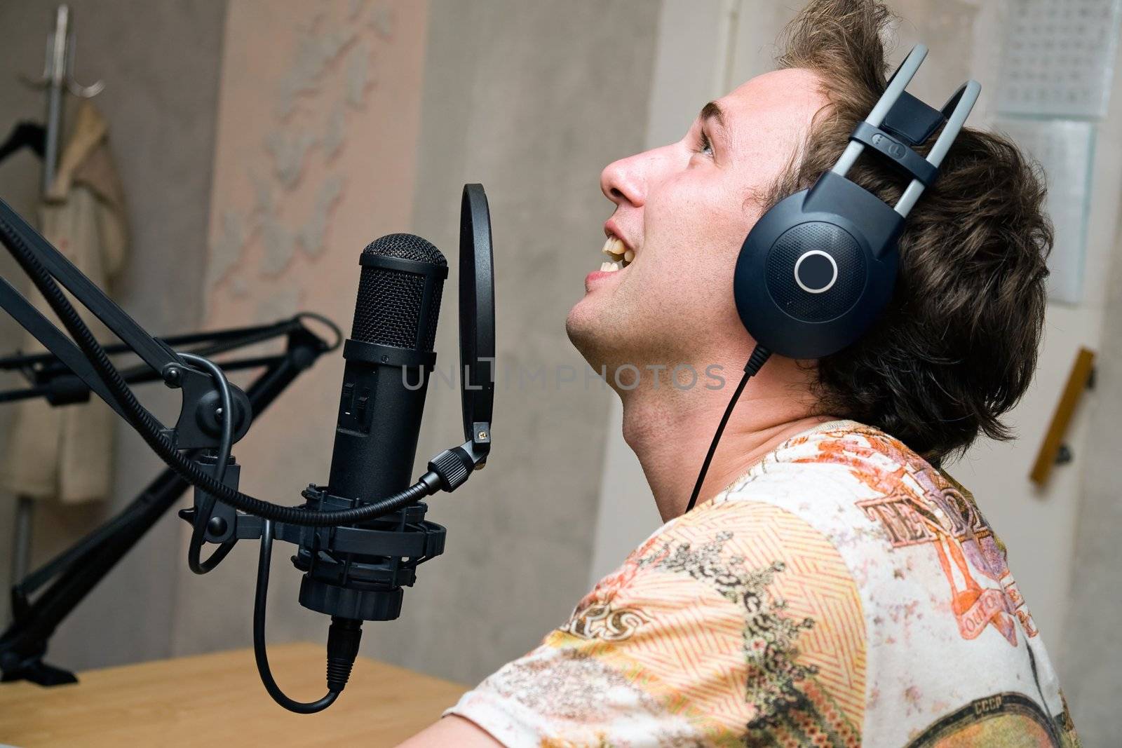 Radio DJ. Young man with microphone and big headphone.