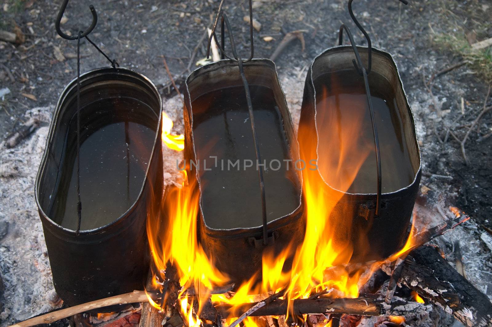 Three kettles warming in the fire in camping