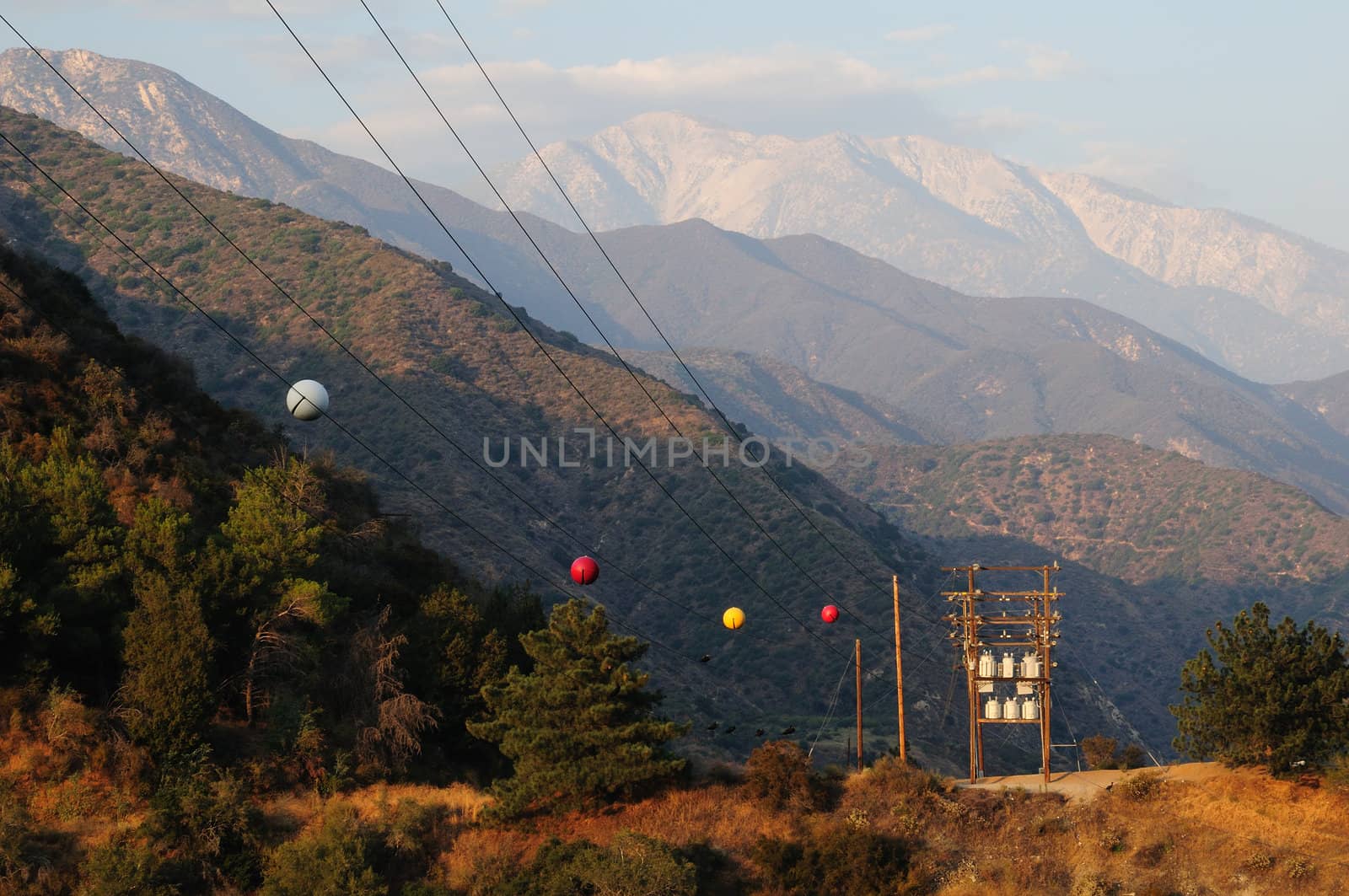 large power line with marker balls travels through the mountains