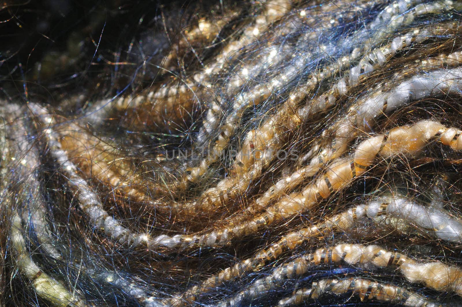close-up (macro) of blue and yellow mohair yarn wrapped in gold strands, forming a wave pattern