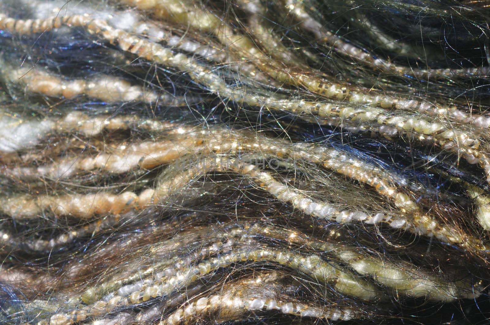 close-up (macro) of blue and yellow mohair yarn wrapped in gold strands, forming wavy lines