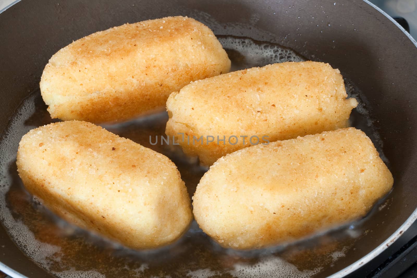 closeup of four potato croquettes cooked on a frying pan