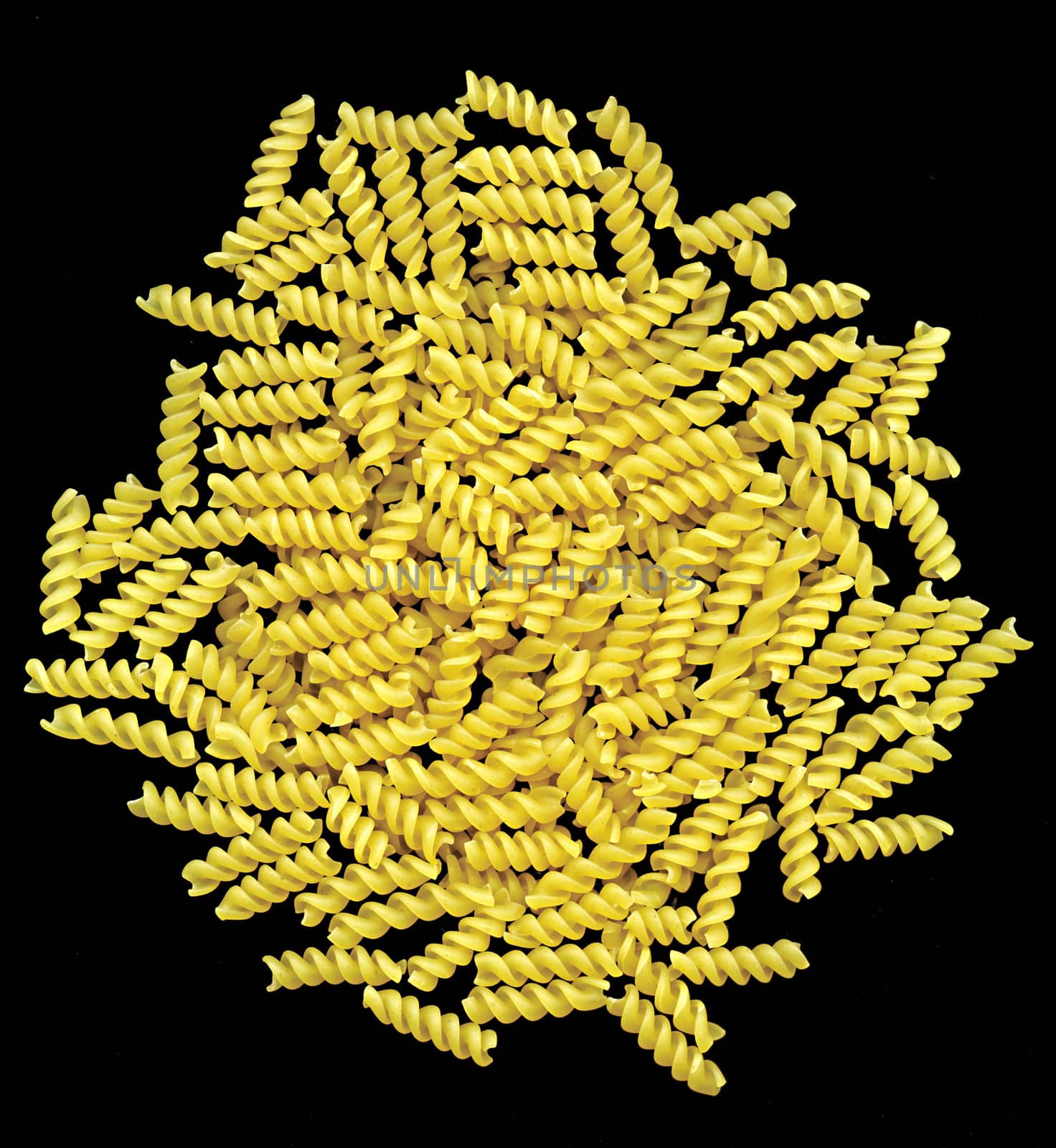 A heap of rotini pasta on black background