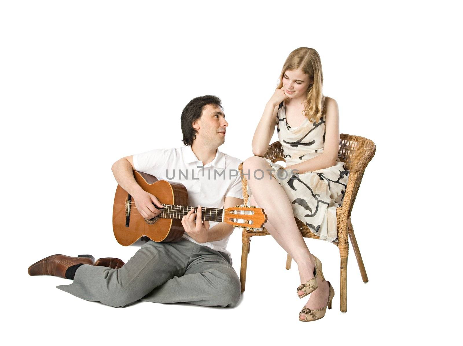 A blond girl and a man playing guitar for her