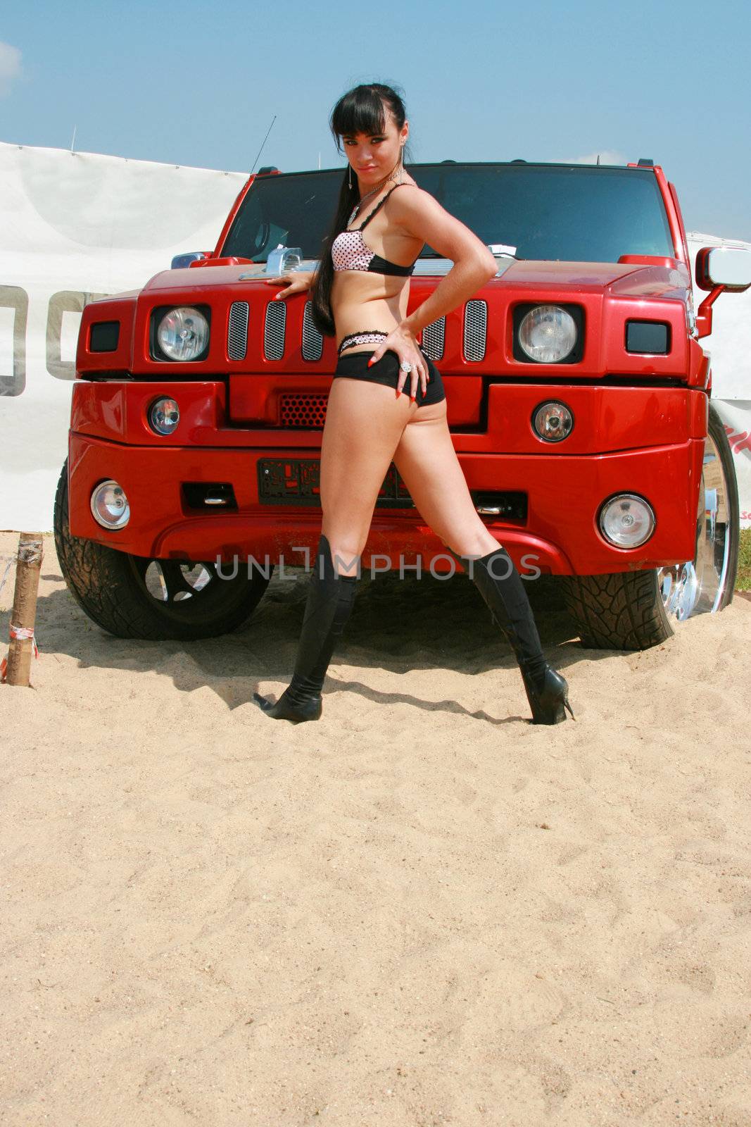 The girl poses in front of the beautiful car