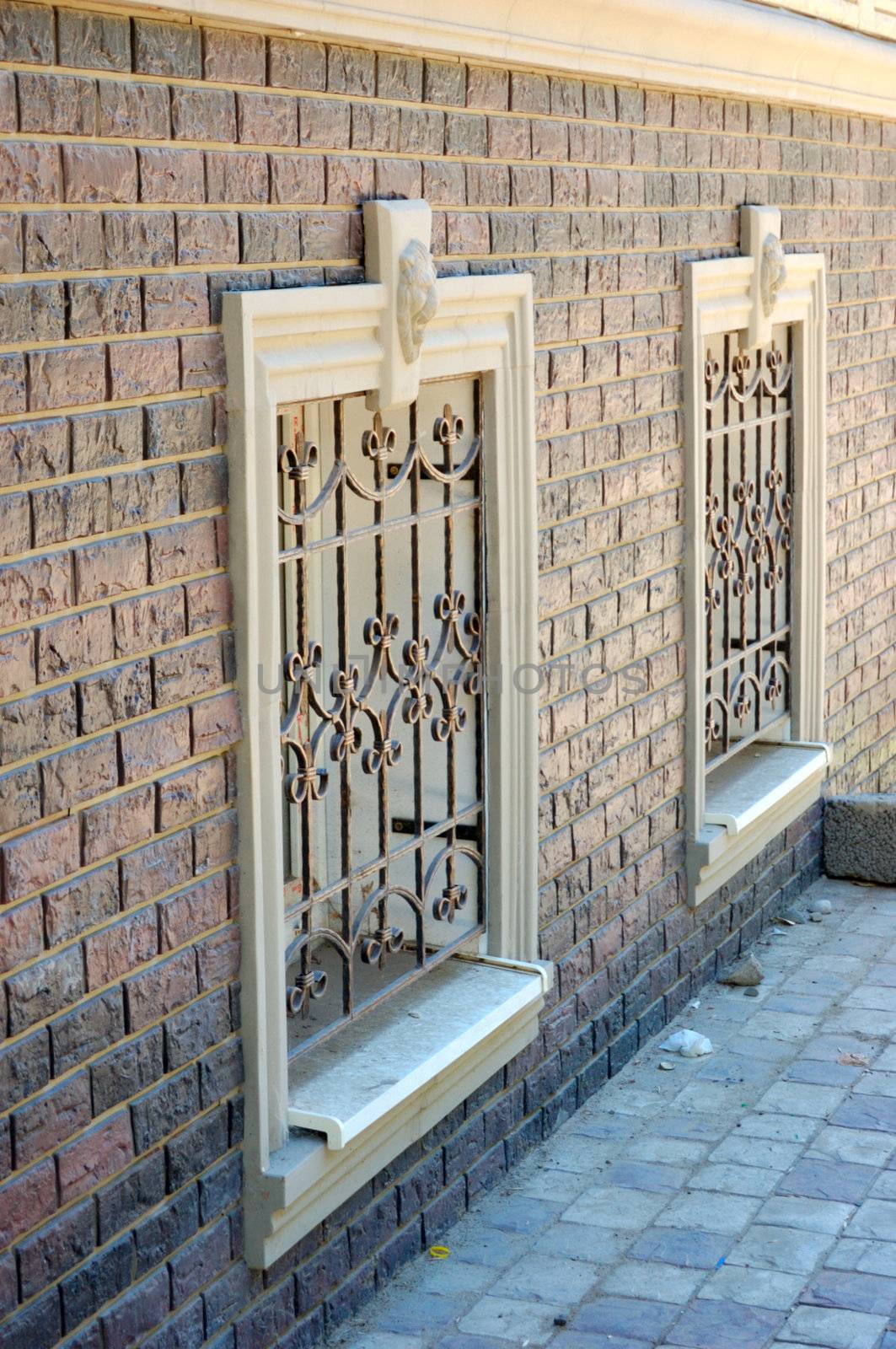 old-style wall, two windows with forged grills and pavement
