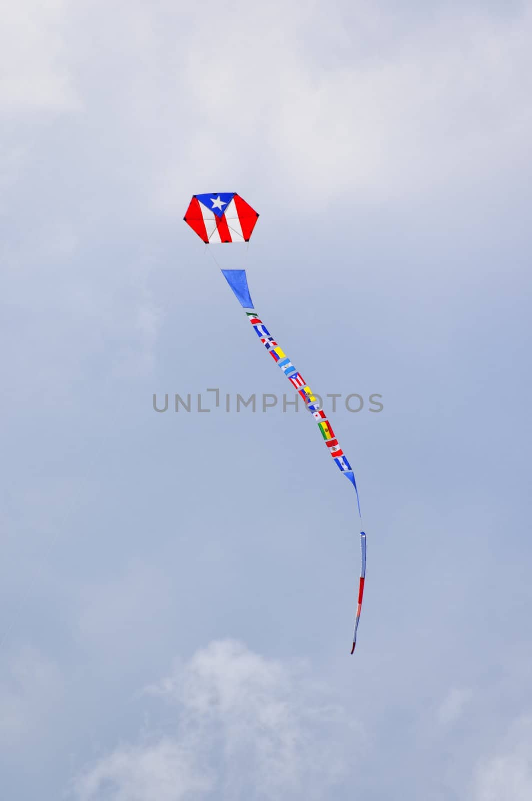 Airborne kite with Puerto Rican flag printed on body, and flags of other Latin American countries forming a long tail.