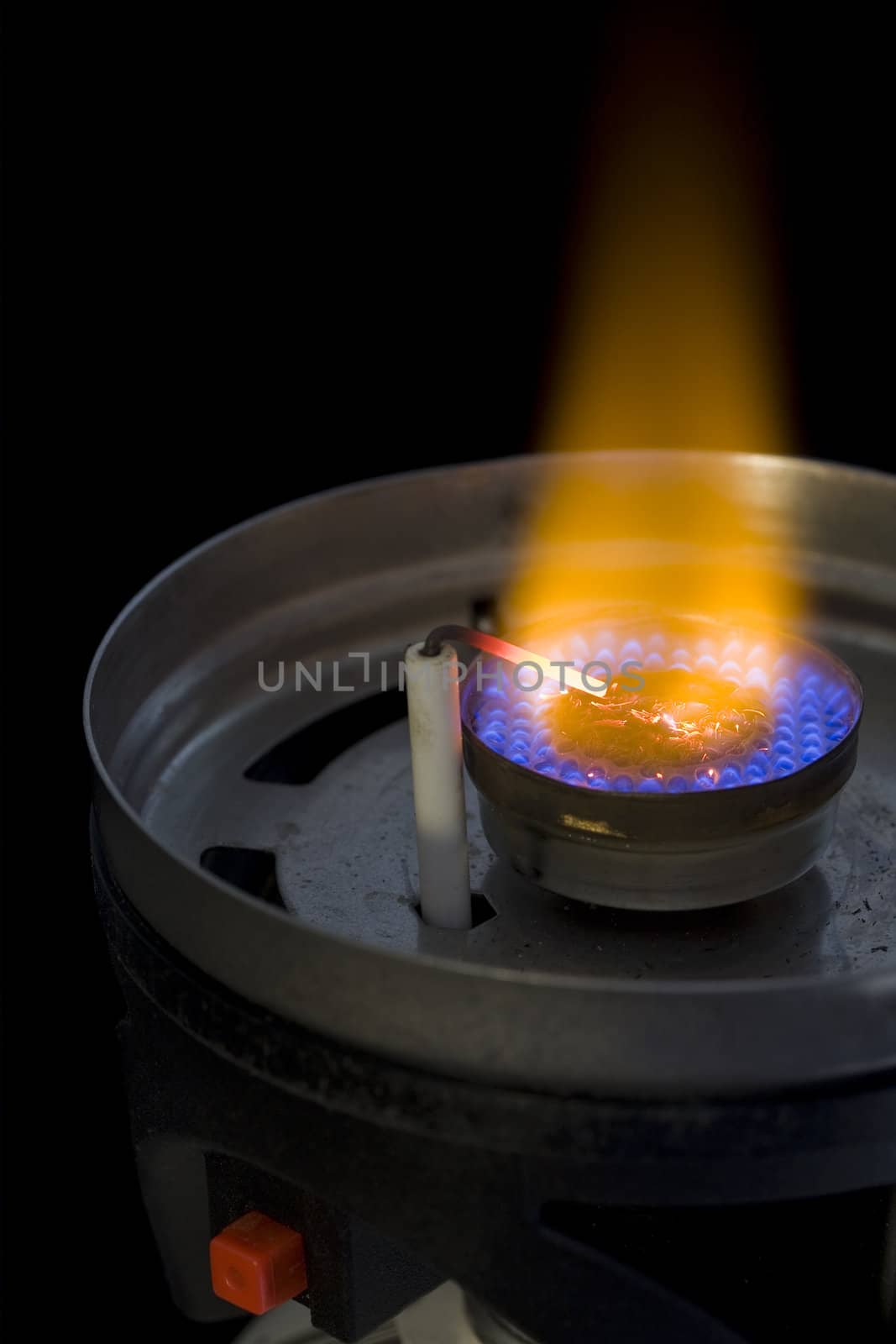 flame burner of camping or backpacking stove with a piezoelectric igniter against black background