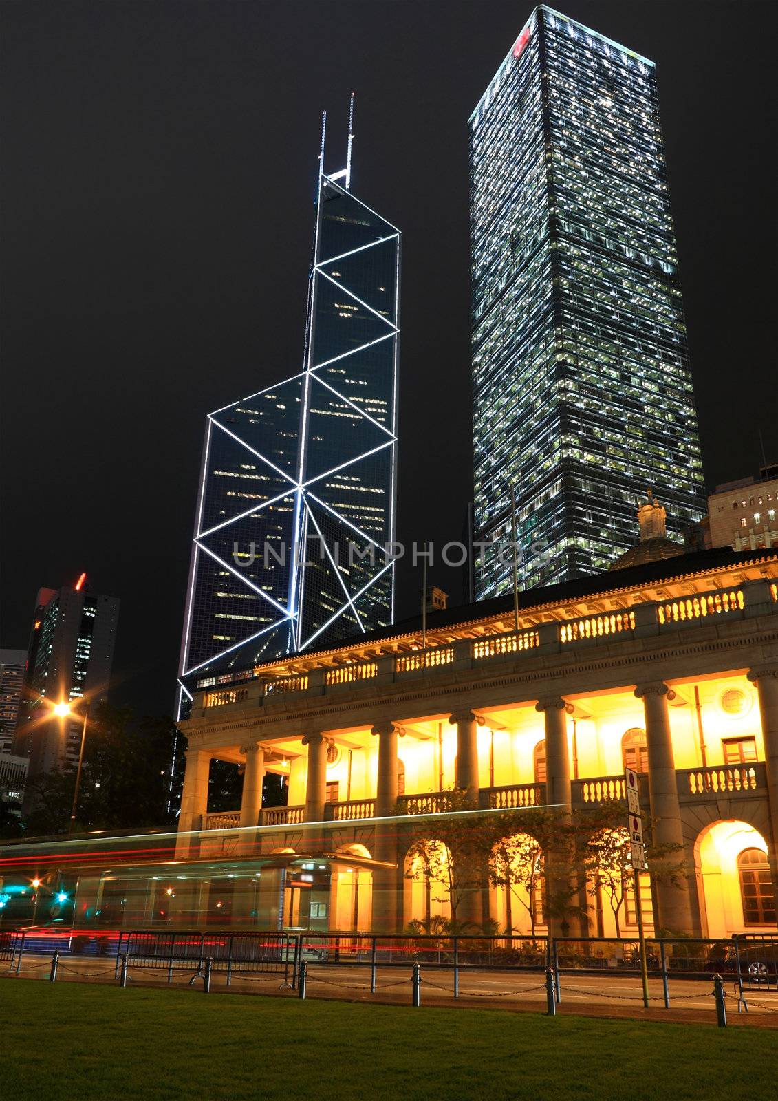 It is night scene of two skyscrapers behind a English building in Hong Kong